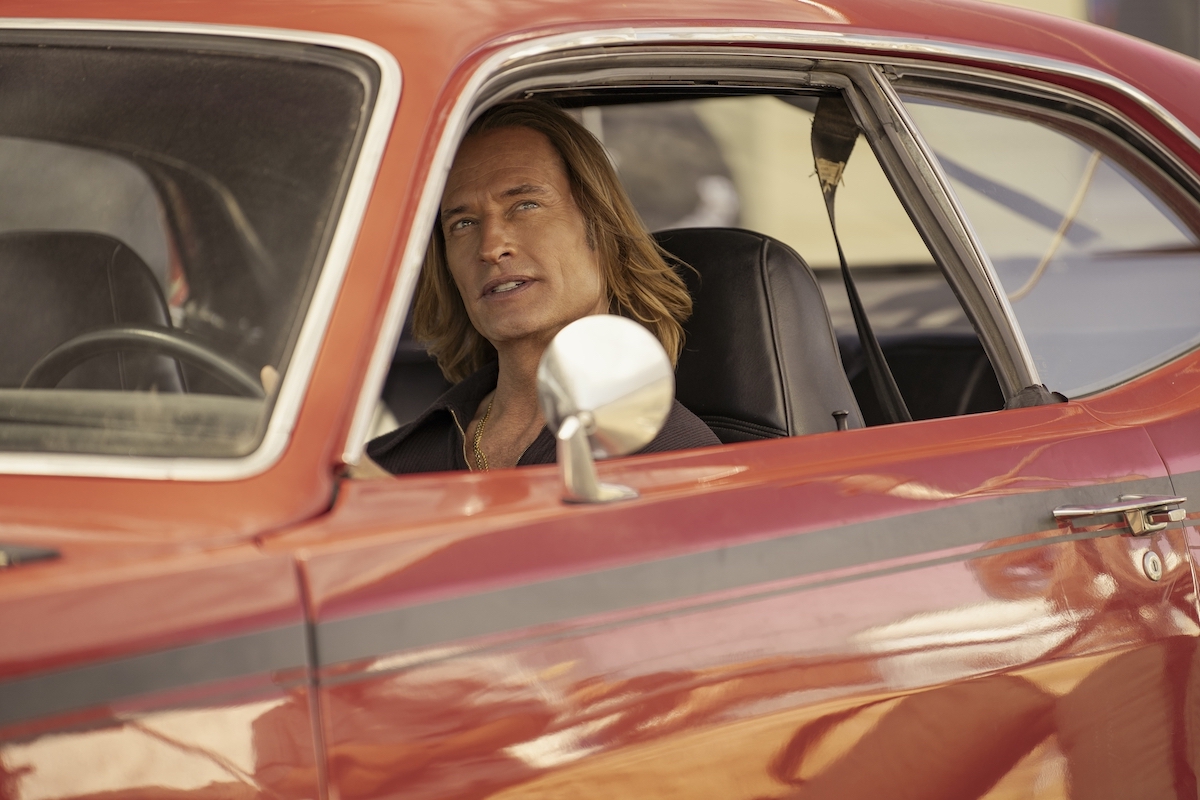 Josh Holloway in 'Duster,' as Jim Ellis shown sitting in a shiny red Plymouth Duster muscle car