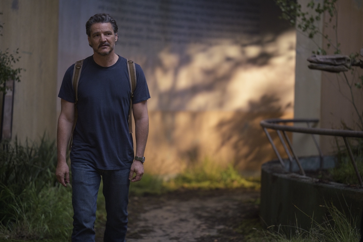 Pedro Pascal in 'The Last of Us' Season 2, Episode 6, as Joel wearing a backpack and t-shirt, walking through an old museum