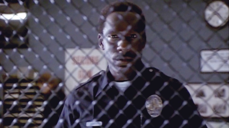 Officer Franklin Rose standing behind a fence in "Cop Rock"