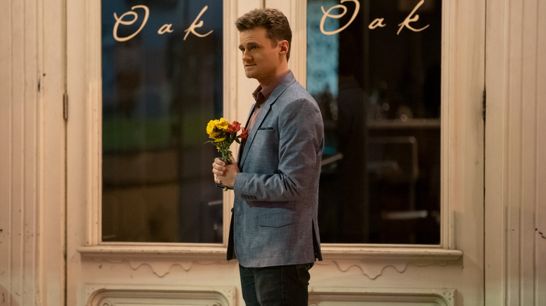 Ben standing outside a restaurant with a bouquet of flowers in "Dating Around"