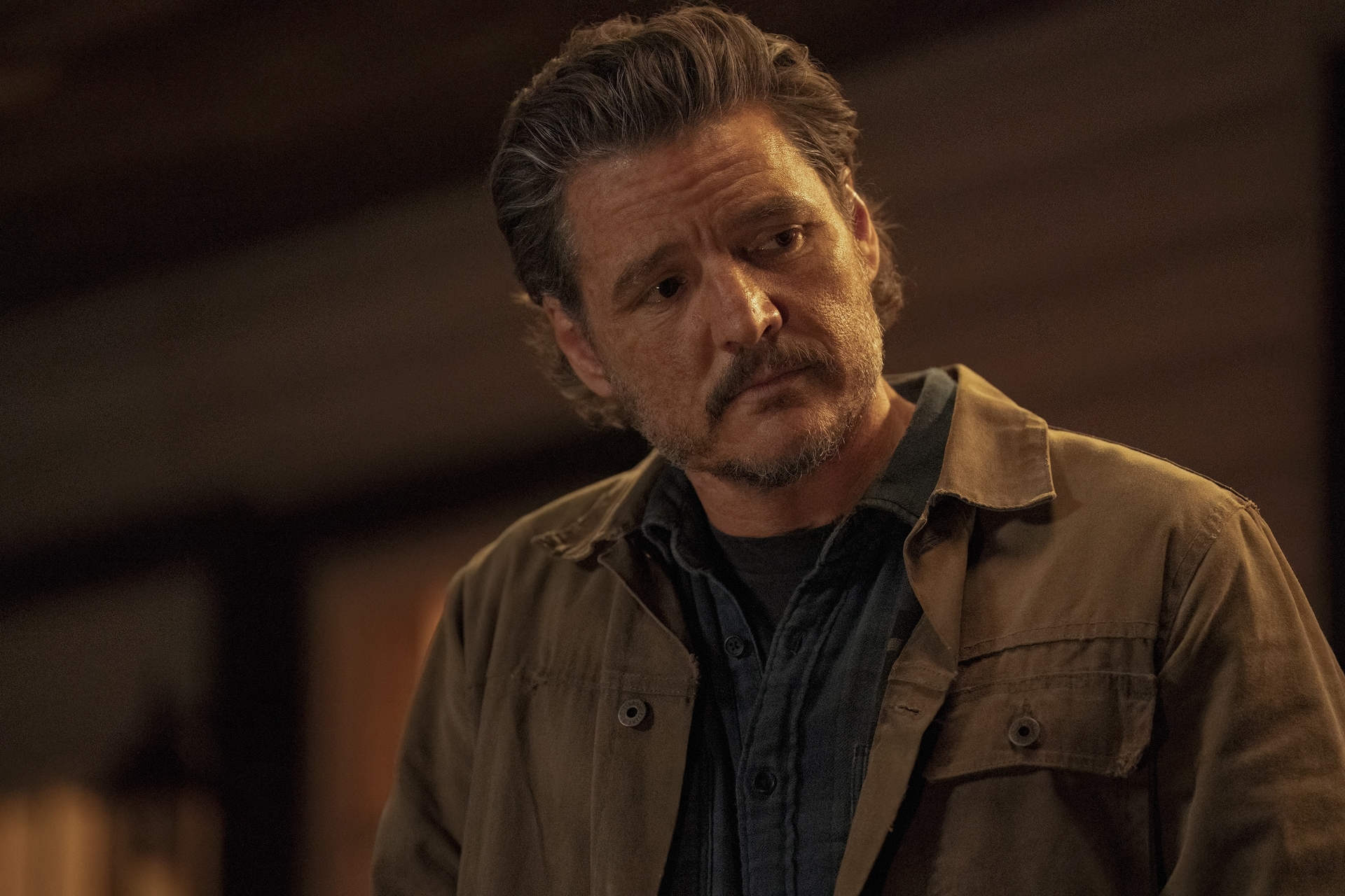 Pedro Pascal as Joel in 'The Last of Us' standing on his porch and looking offscreen.