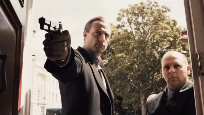 Archy with a gun and his associate in a doorway in RocknRolla (2008)