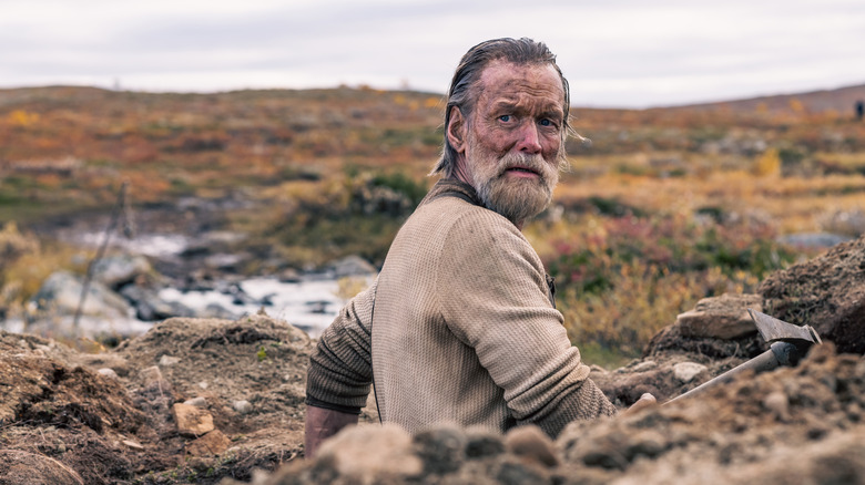 Aatami Korpi looking back while standing in a hole in "Sisu" (2022)