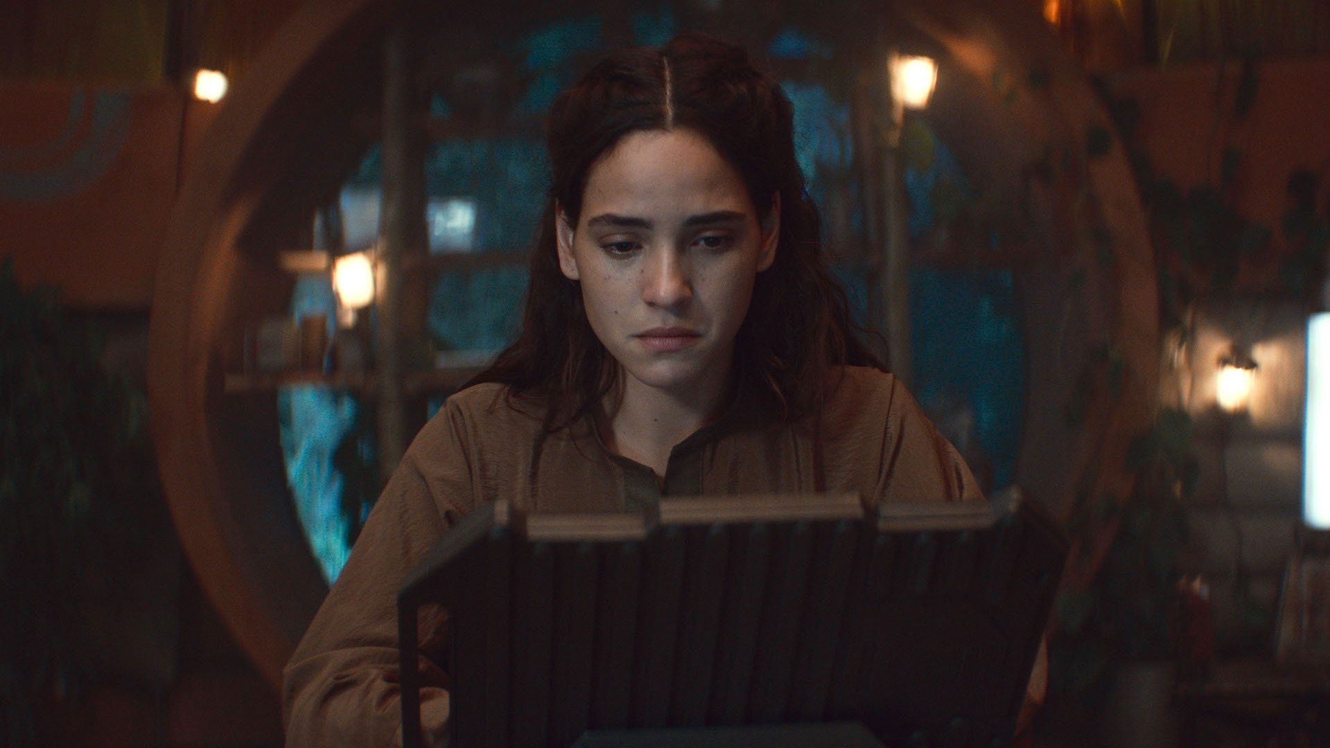 A woman looking into a futuristic computer; Adria Arjona in Lucasfilm's 'Andor' Season 2