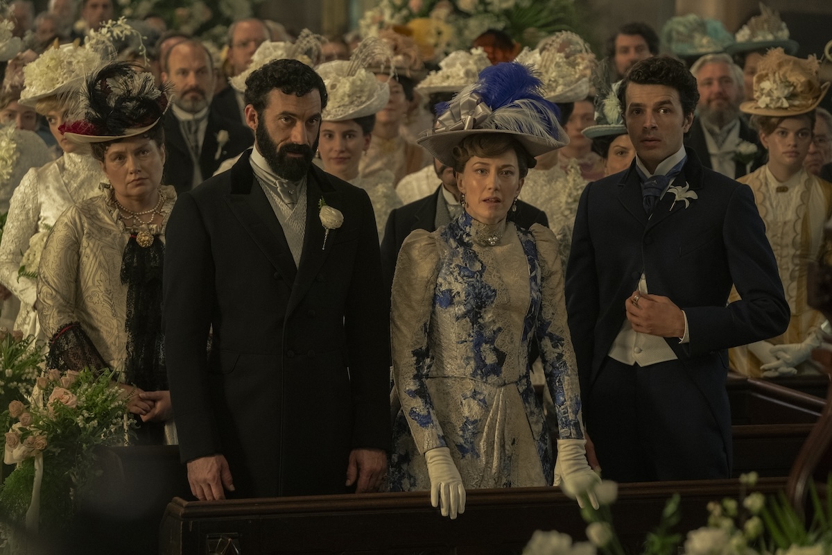'The Gilded Age' Season 3 stars Merritt Wever, Morgan Spector, Carrie Coon, and Harry Richardson, shown here standing at the front of a crowd in church, looking concerned