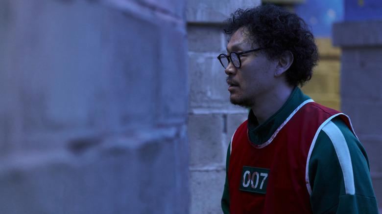 Yong-sik staring into a room during hide and seek in Squid Game