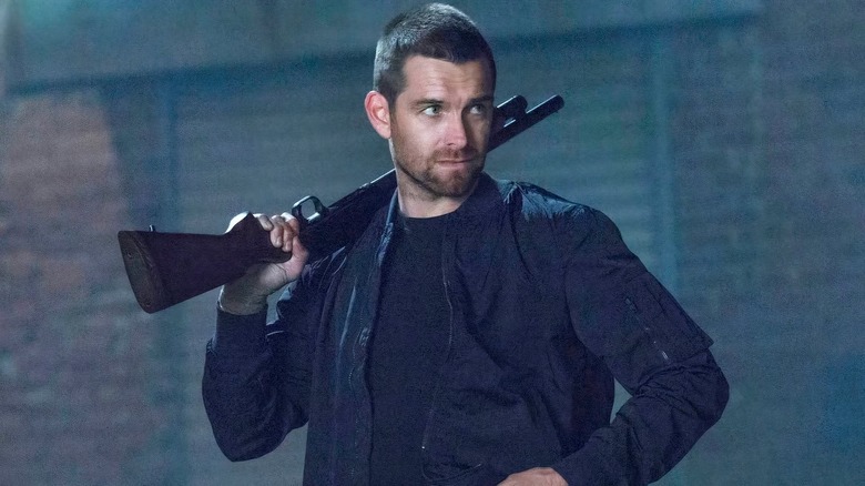 Lucas holding a rifle on his shoulder in "Banshee."