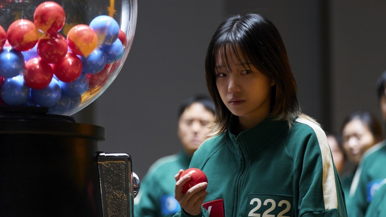 Jun-hee holding a red ball from a machine in Squid Game