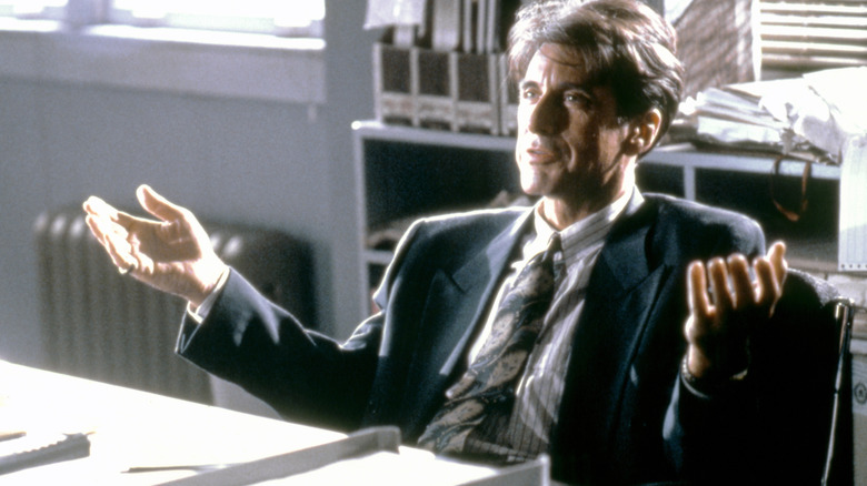 Richard gestures while sitting at his desk in Glengarry Glen Ross (1992)