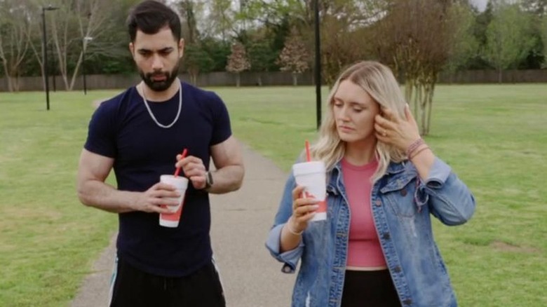 Mahdi and Stevi walking with drinks outside in "90 Day Fiance"