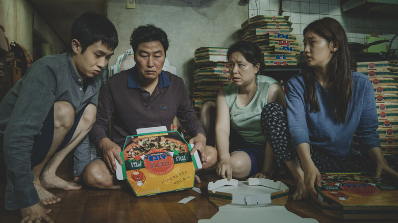 Kim Ki-taek and his family folding pizza boxes on floor in "Parasite" (2019)