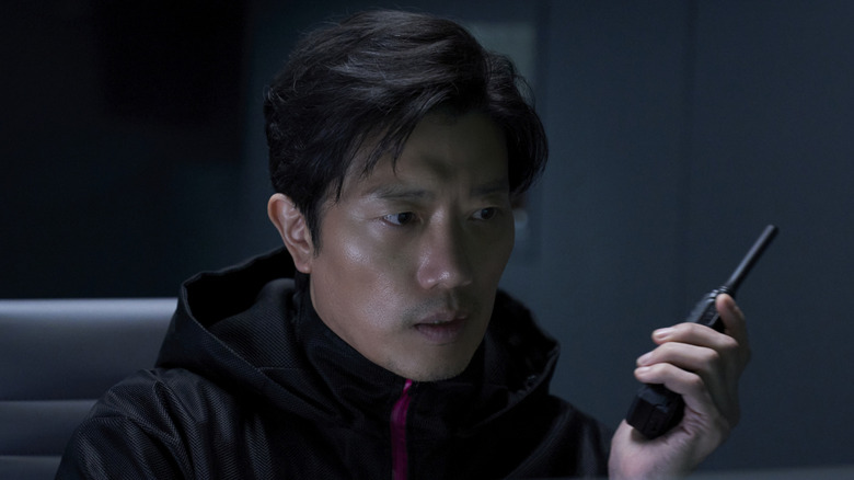 Hwang In-ho listens to his walkie-talkie in "Squid Game" (2021-2025)