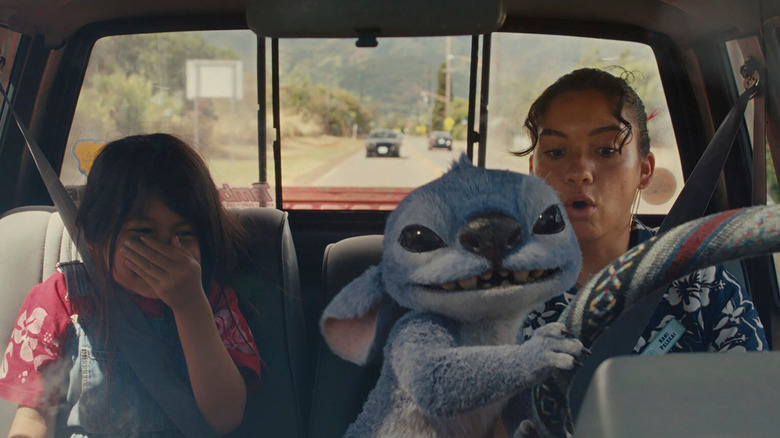 Stitch grabs the steering wheel in Nani's car while Lilo covers her face in "Lilo and Stitch" (2025)