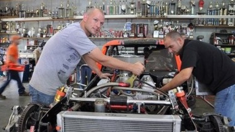Mechanics working on modified NASCAR racers in garage