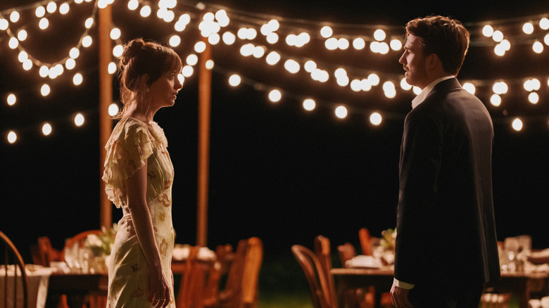 Lucy and John talk by outdoor dining tables and stringed lights at night in "Materialists" (2025)