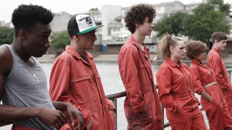 A group of young adults in orange jumpsuits leaning against a railing in "Misfits."