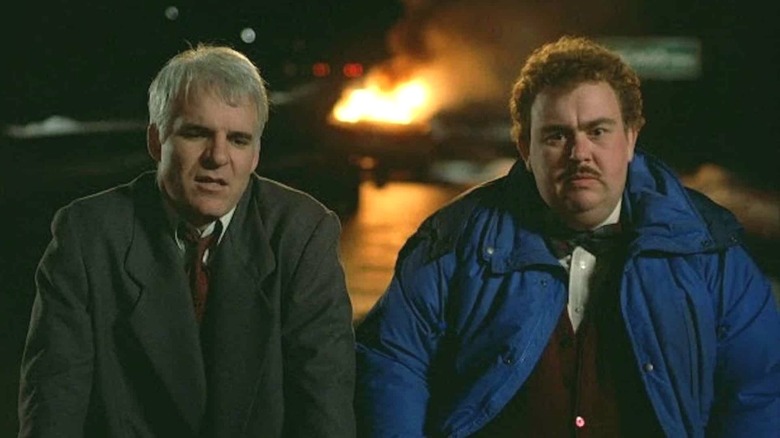 Neal and Del sitting as their car burns in "Planes, Trains and Automobiles"