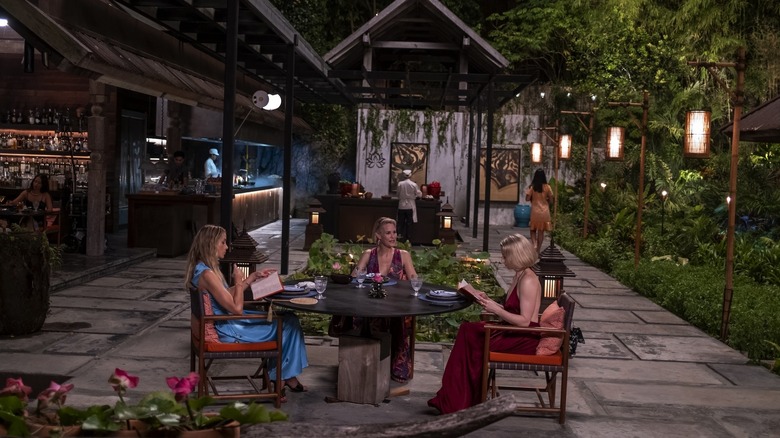 Three guests dining outdoors in "The White Lotus"
