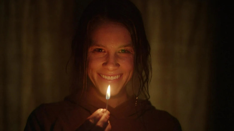 Rose holds up a match and smiles in "Smile" (2022)