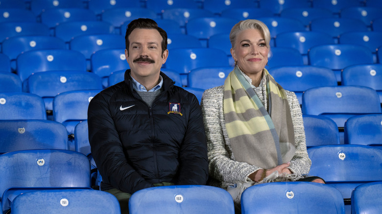 Ted and Rebecca sitting in the stands smiling on Ted Lasso