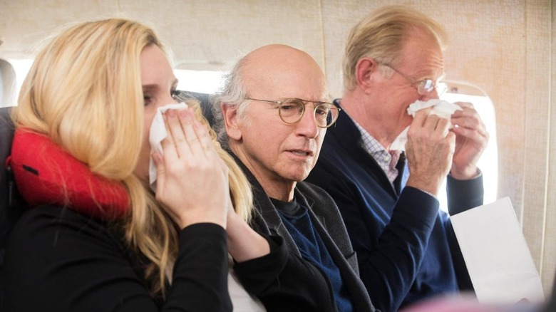 Larry sits between two sneezers on a plane in "The Accidental Text on Purpose"
