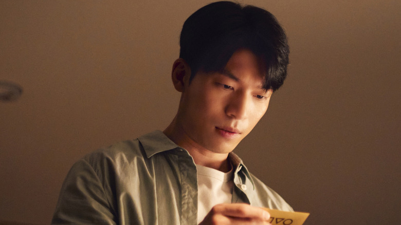 Jun-ho looking at a Squid Game bank card on Squid Game