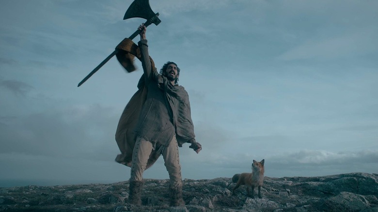 Gawain holding the Green Knight's axe and the fox in The Green Knight (2021)