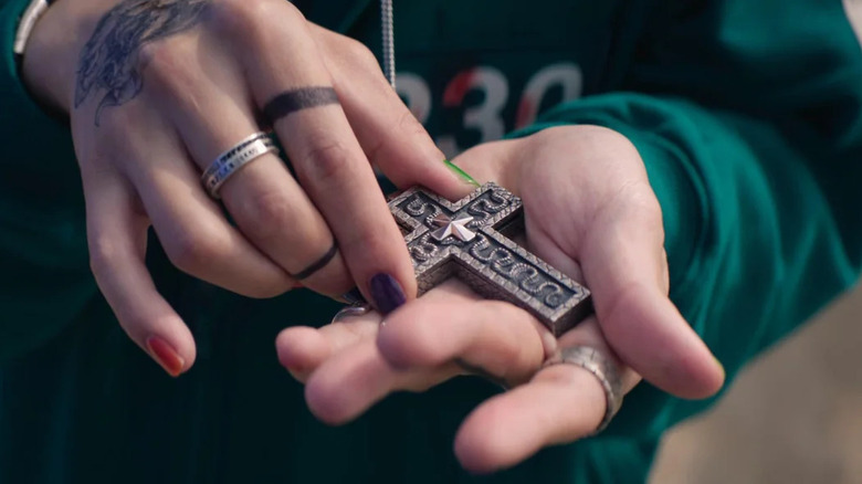 Thanos holding his cross necklace on Squid Game Season 2