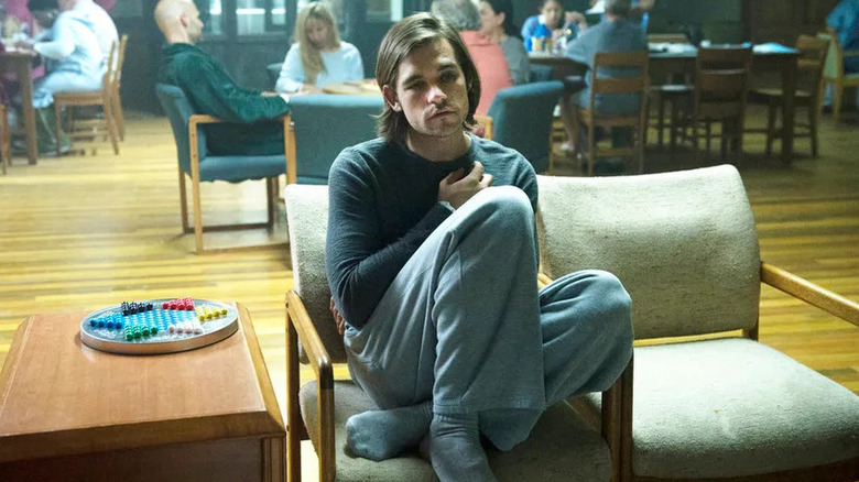 Quentin sitting in a chair with a frown in "The Magicians."