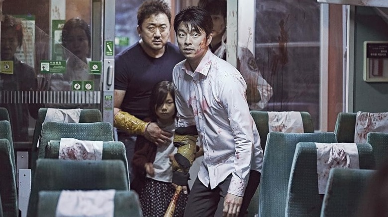 Seok-woo, Su-an, and Sang-hwa stand ready in a train car aisle in "Train to Busan" (2016)