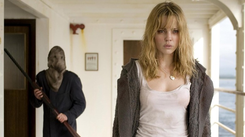 The masked killer holds a shotgun behind Jess in "Triangle" (2009)