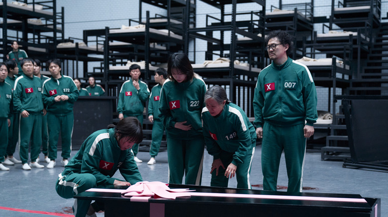 Players surrounding a gift-wrapped coffin on Squid Game