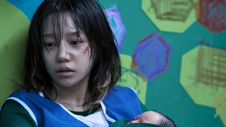 Jun-hee sitting holding her baby in "Squid Game"