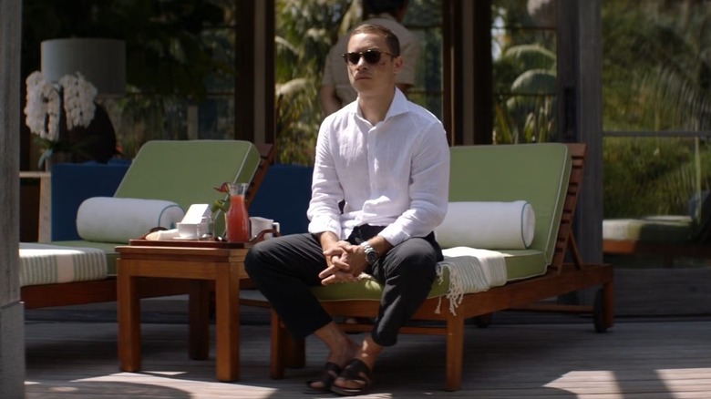 J sitting alone by a pool in the Virgin Islands in "Animal Kingdom"