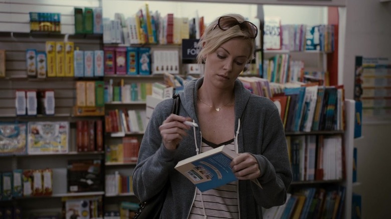 Mavis (Charlize Theron) writing in a book she hasn't paid for inside of a bookstore