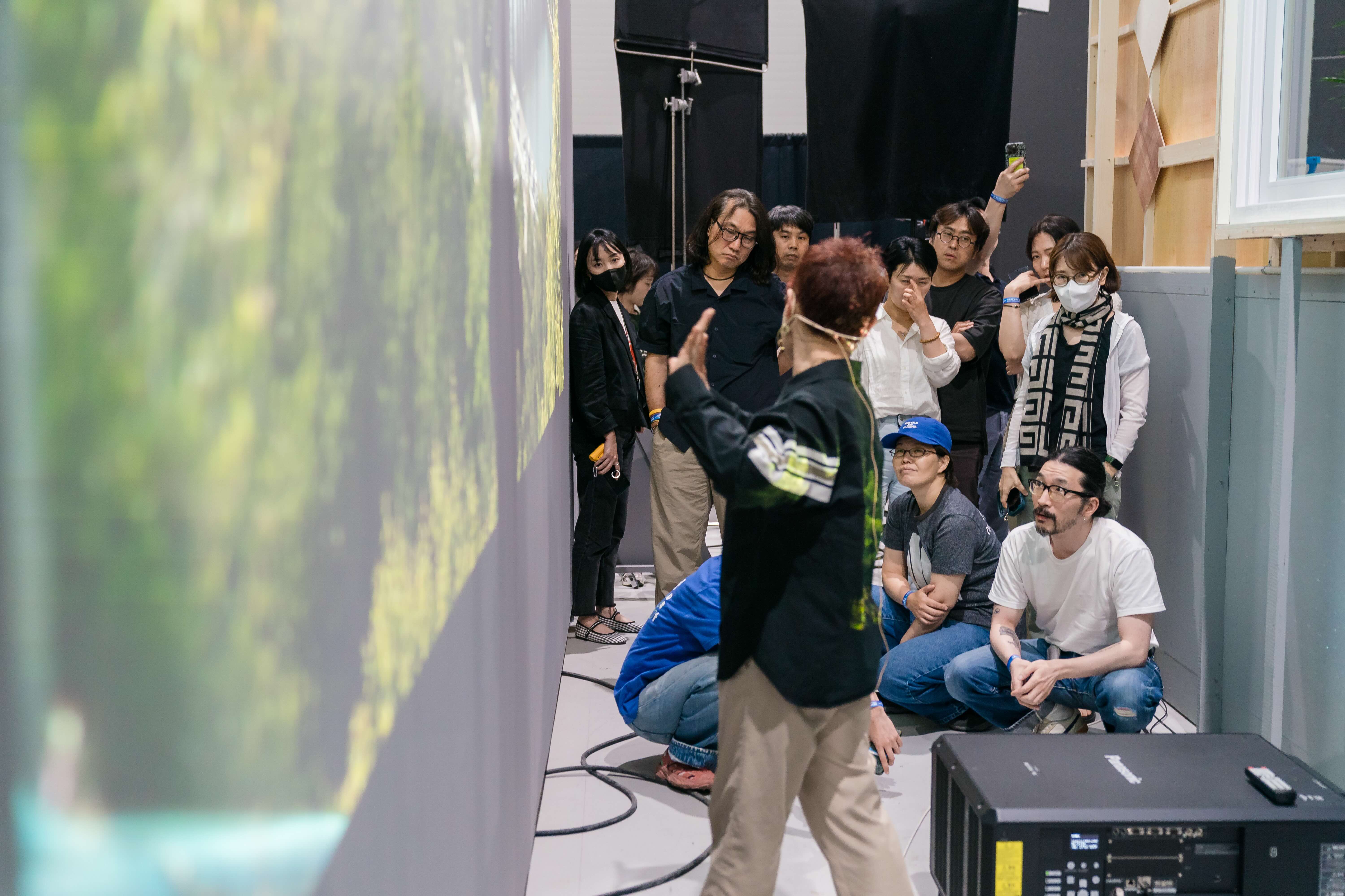 Students and instructors at the Netflix VFX Academy in Japan. An instructor gestures at an LED wall while students look on. 