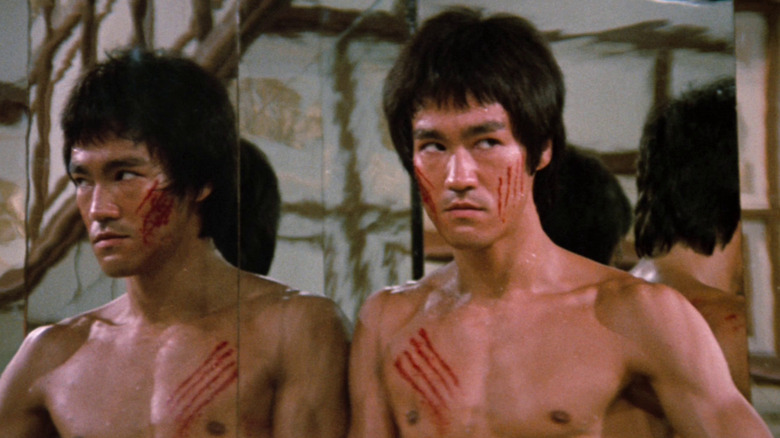 Lee stands next to a mirror in "Enter the Dragon" (1973)