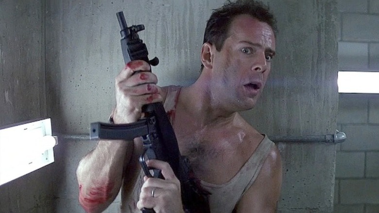 John McClaine peers around a corner with a submachine gun in "Die Hard" (1988)
