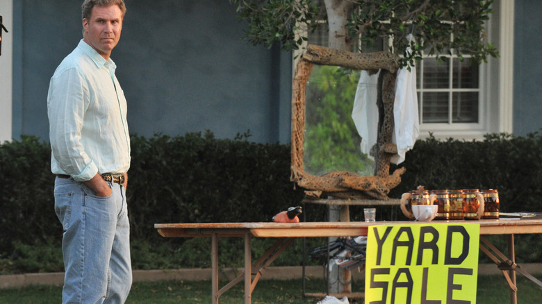 Nick standing in front of a table with a yard sale sign in Everything Must Go (2010)