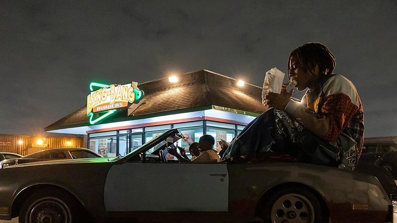 The giant Cootie sits in the trunk of a car eating outside Bing-Bang Burgers in "I'm a Virgo" (2023)