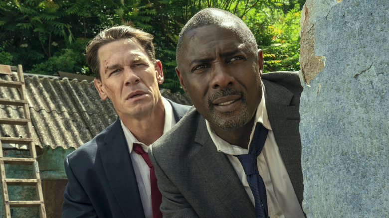 Derringer and Clarke peek out from behind a wall in "Heads of State" (2025)