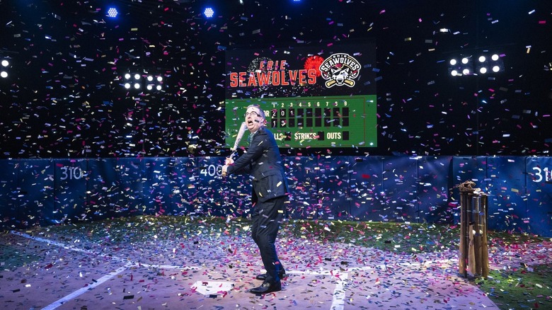 Host John Oliver announcing the show's new minor league baseball team partner and holding a bat at the home plate of an elaborate stage recreation of a baseball field on "Last Week Tonight with John Oliver"