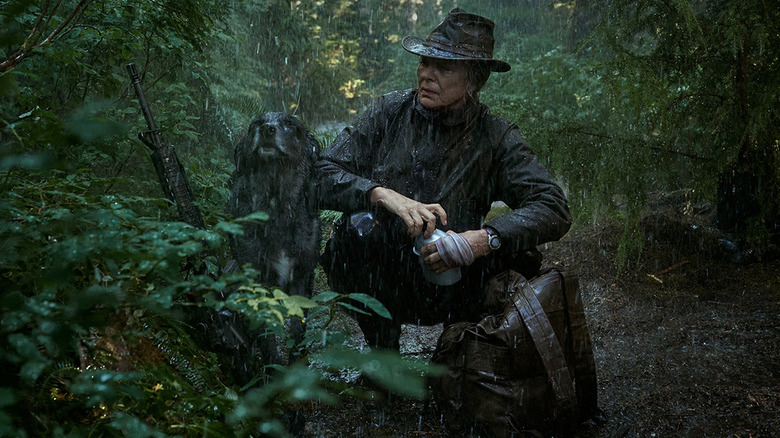 Lou and her dog stop in the woods in the rain in "Lou" (2022)