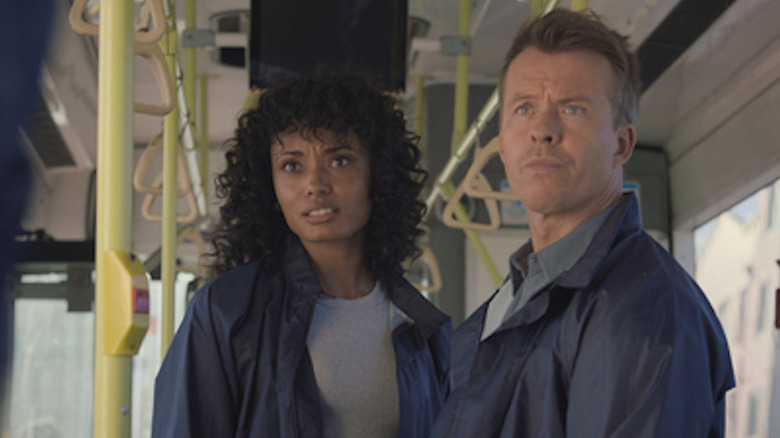 Michelle and JD stand on a bus looking offscreen in "NCIS: Sydney" (2023-present)
