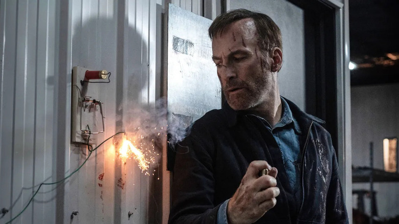 Hutch lights a fuse against a metal wall in "Nobody" (2021)
