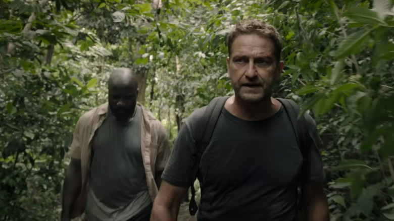 Torrance and Gaspare walk through the jungle in "Plane" (2023)