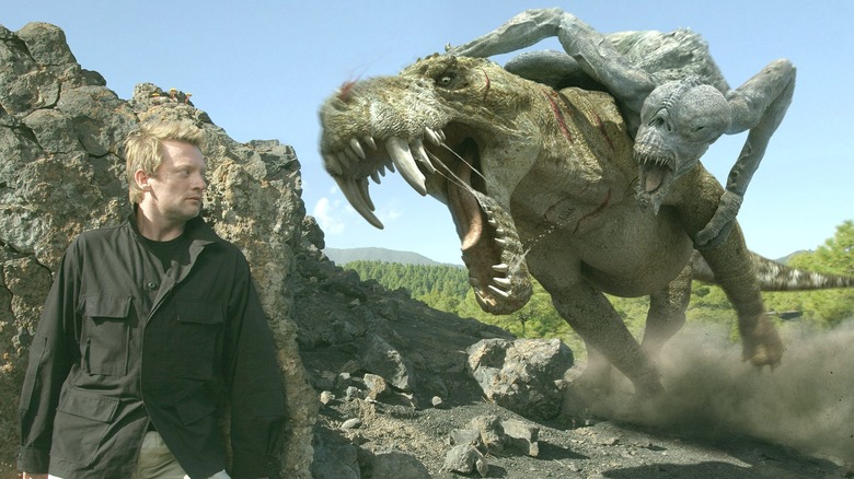 Nick Cutter hiding behind a rock as monsters fight in "Primeval"