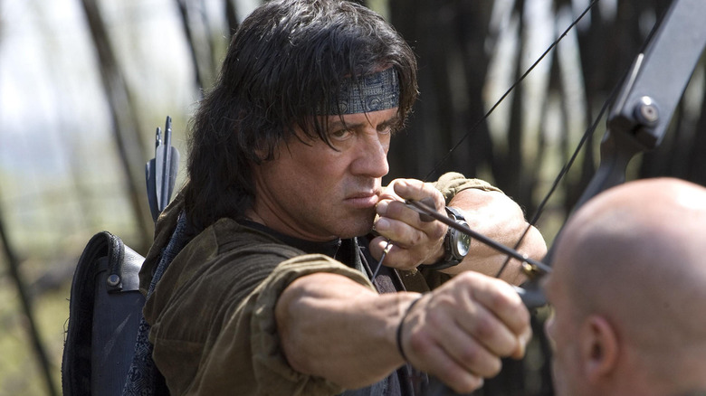 Rambo points an arrow at a man's head in "Rambo" (2008)