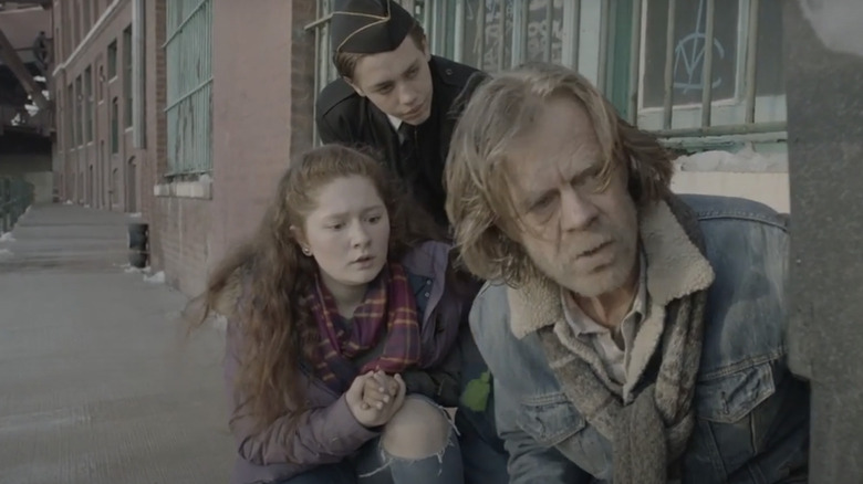 Frank, Carl, and Debbie sneak around behind a dumpster in Shameless