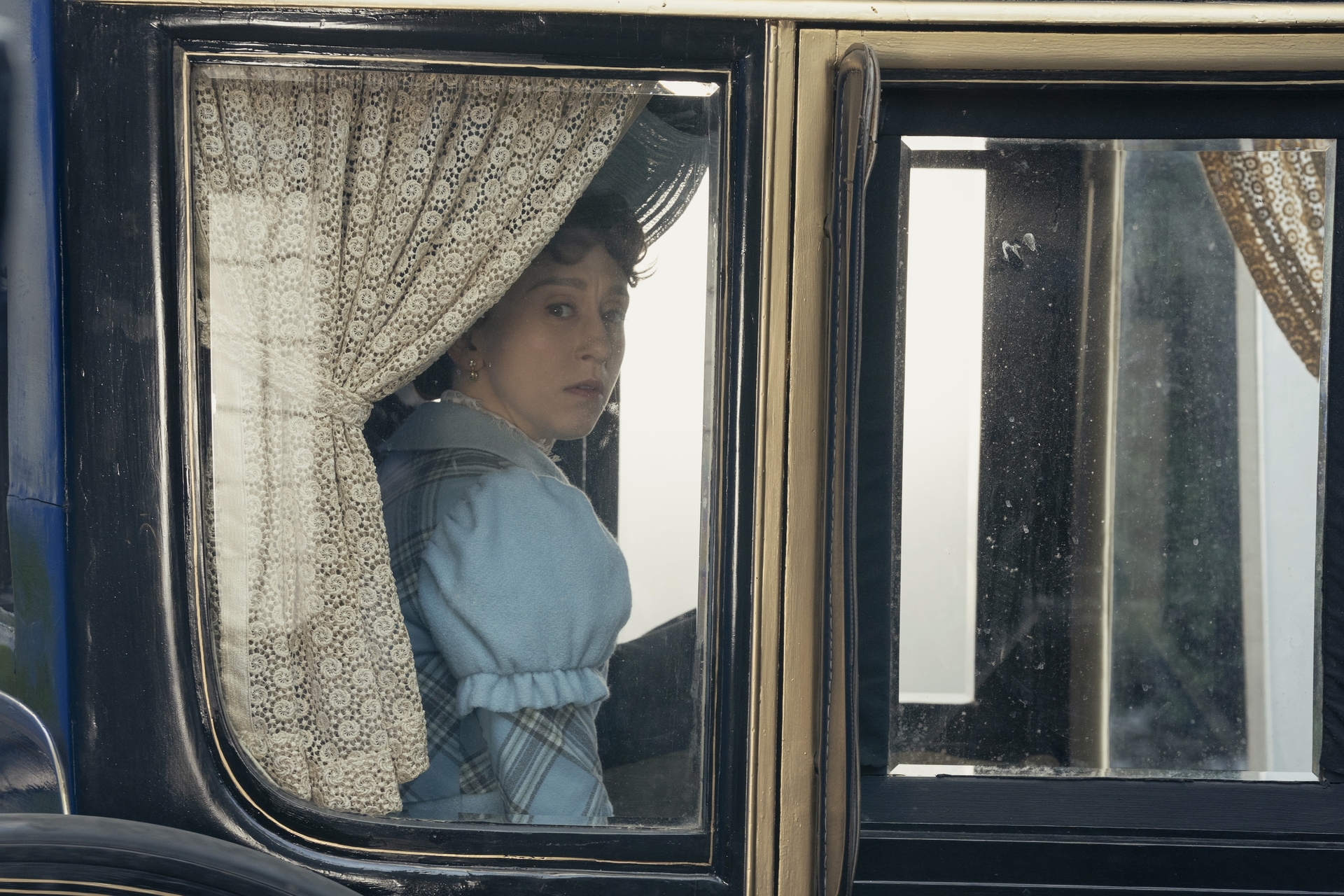 Taissa Farmiga in 'The Gilded Age' Season 3 looking sadly out from the window of a carriage. 
